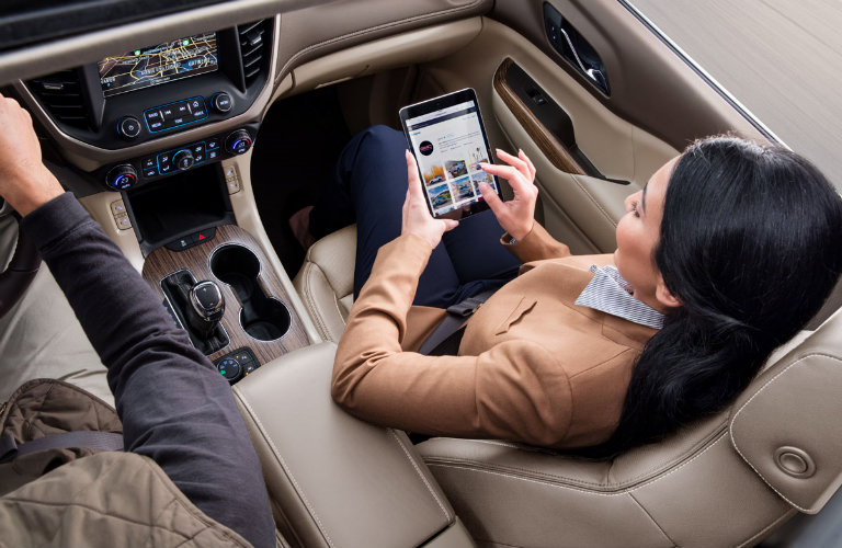 woman sitting in passenger seat of car enrolling in My GMC Rewards on tablet